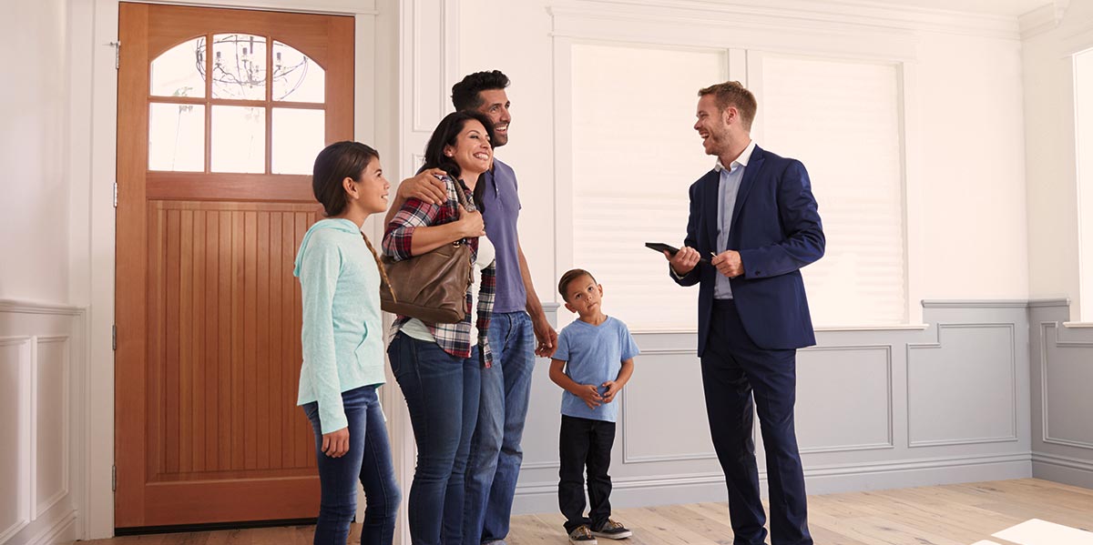 A real estate agent shows a home to a family.